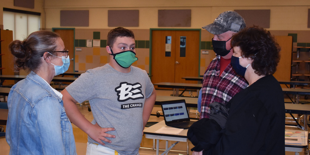 Pathways student and his grandparents talk with a music teacher during open house