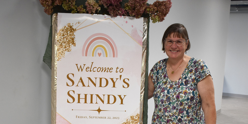Sandy Sherwood next to Sandy's Shindy sign