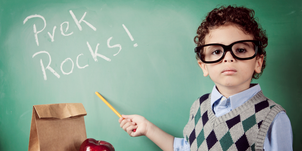 Stock photo of a PreK student pointing to a chalkboard that says "PreK Rocks!"
