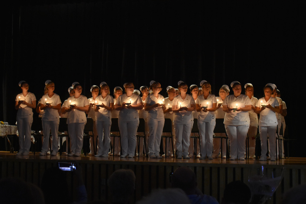 Adult LPN students in candle lighting ceremony on stage at graduation
