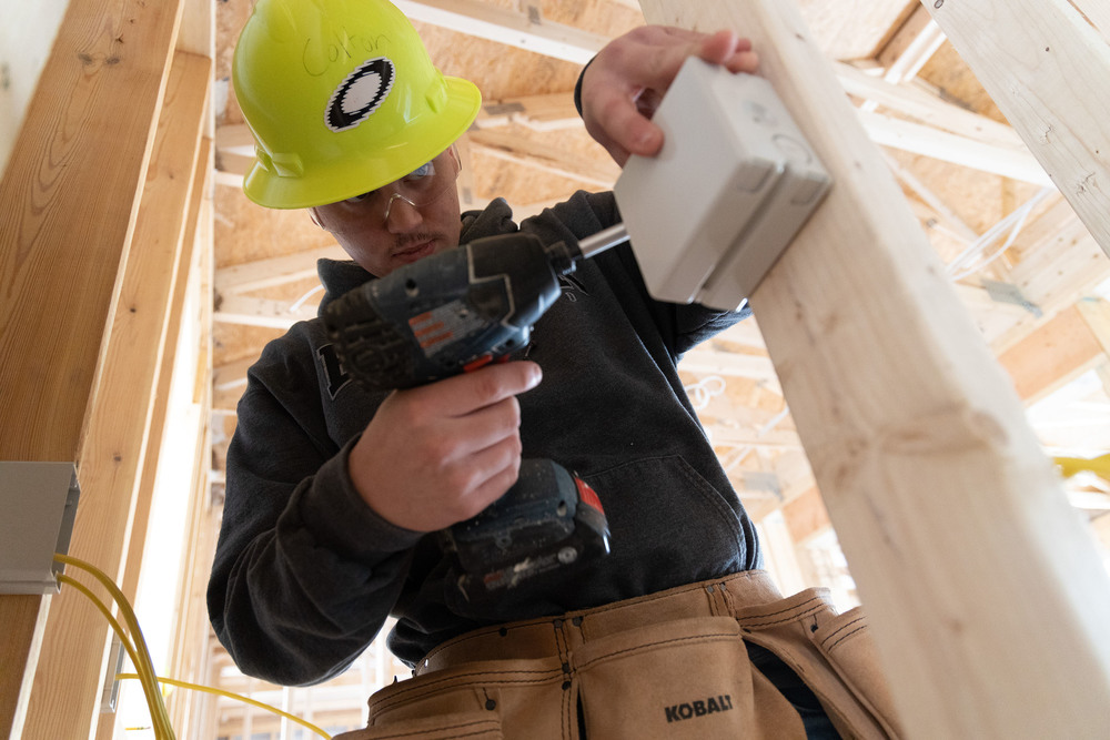 Building Construction student drilling while working on a house