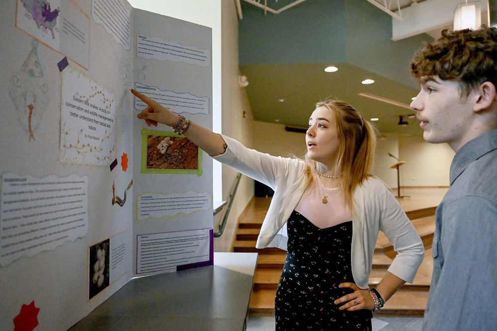Student points at her project as another student looks on