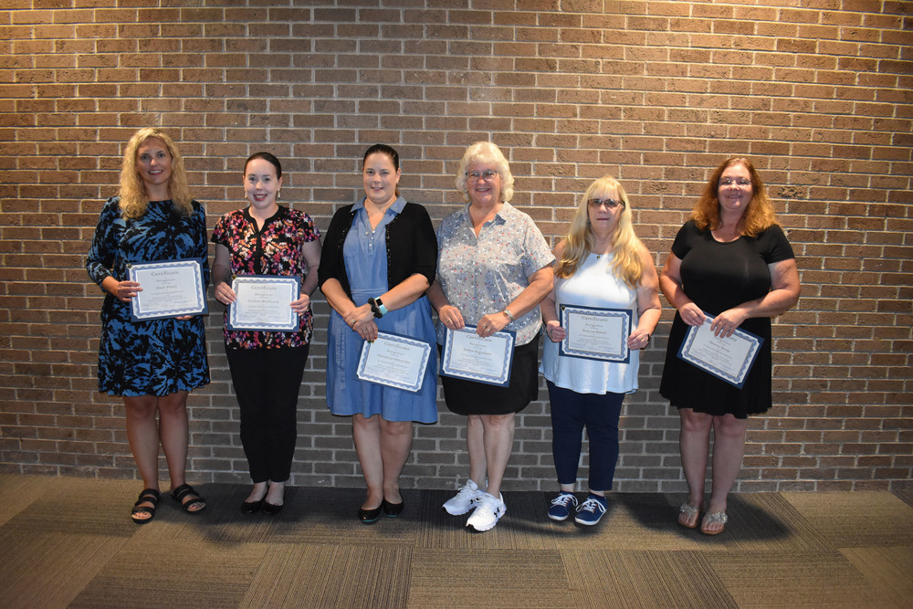 Six staff members holding certificates for their years of service