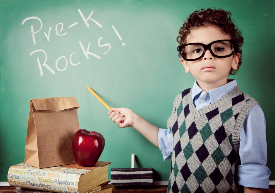 Pre-K Rocks stock photo of a child in glasses pointing at a chalkboard