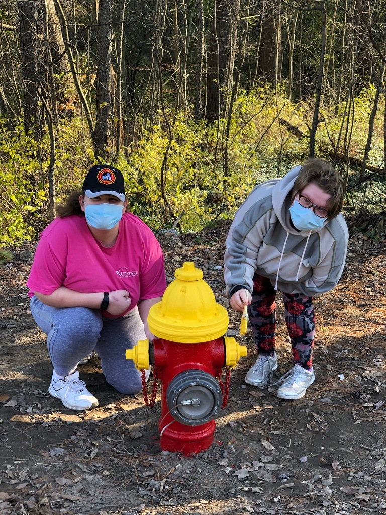 Students painting a fire hydrant red and yellow