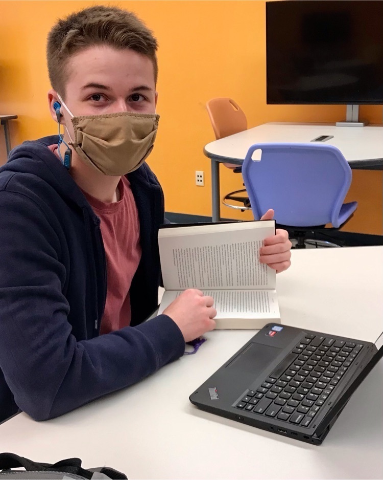 Student holding a book next to laptop
