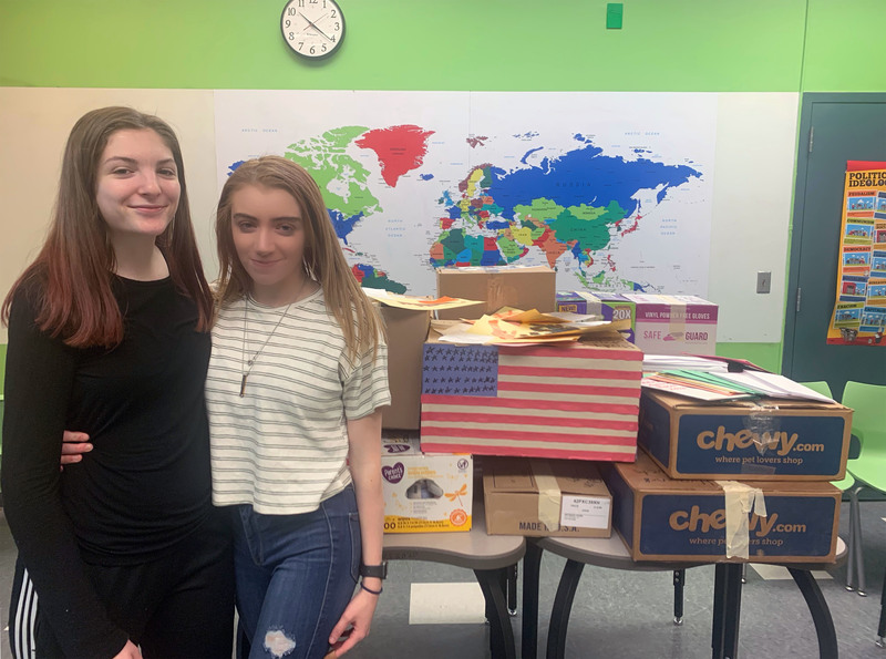 Two students standing by boxes of donated items 