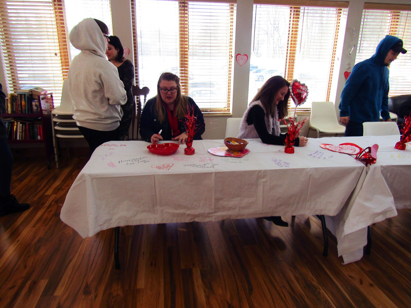 Pathways students and staff write Valentine's Day messages on a table for The Grand residents