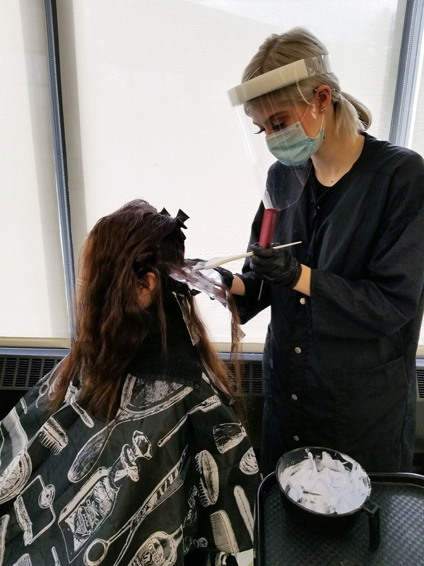 Cosmetology students does a foil highlight for a customer