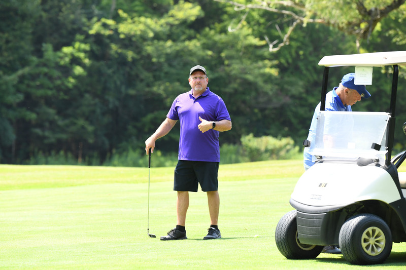 Two golfers on the course by a golf cart