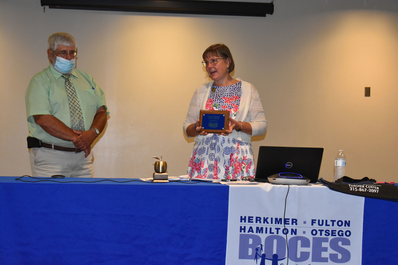 Thomas Shypski and Sandy Sherwood hold up a plaque for Diane Tooley's 30 years at Herkimer BOCES