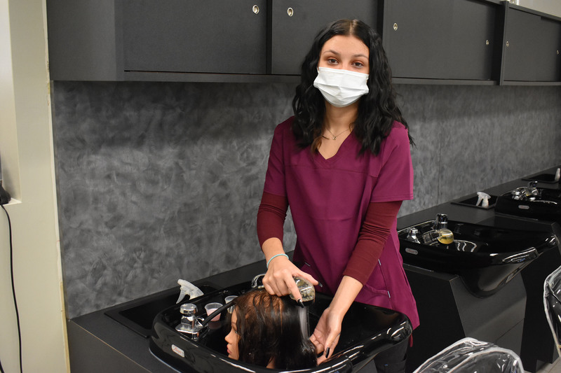 Cosmetology student washes out the hair of a mannequin head