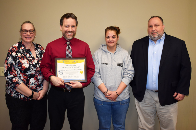 Four Safety Services team members pose together with a safety award certificate