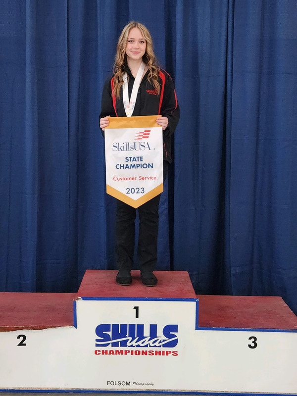 Cosmetology student holding a banner as SkillsUSA state champion in customer service