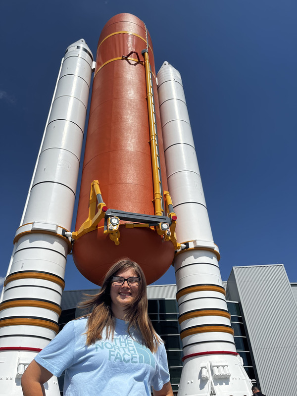 Student standing in front of a space shuttle