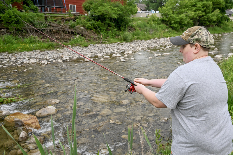 Student casts a fishing pole into Fulmer Creek