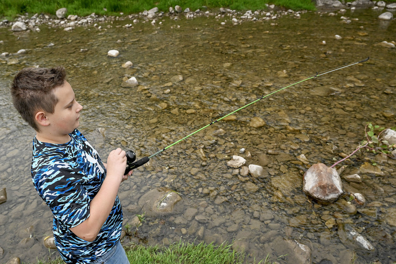 Student casts a fishing pole into Fulmer Creek