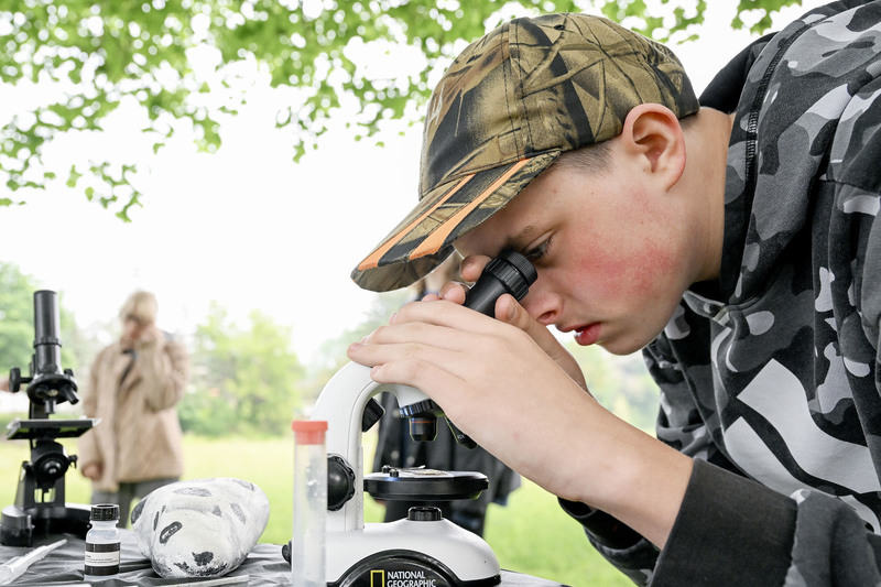Student looks at water sample through microscope