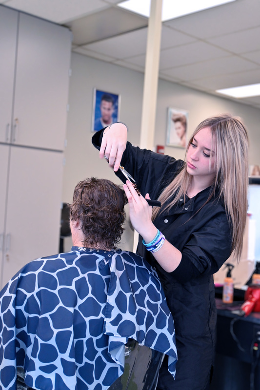 Cosmetology student cutting a patron's hair